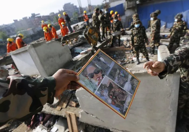 A Nepal army soldier hands over a photo frame to another after collecting it from the rubble of a destroyed house, after the April 25 earthquake, in Kathmandu, Nepal April 29, 2015. (Photo by Adnan Abidi/Reuters)