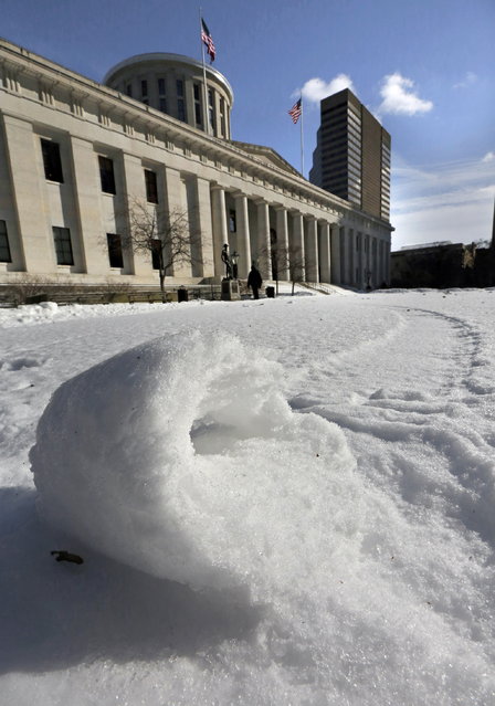 A snowroll appears on the statehouse lawn in Columbus, Ohio, Monday, January 27, 2014. According to the National Weather Service, a snow roller is a rare meteorological phenomenon in which large snowballs are formed naturally when chunks of snow are blown along the ground by wind. (Photo by Tom Dodge/AP Photo/The Columbus Dispatch)