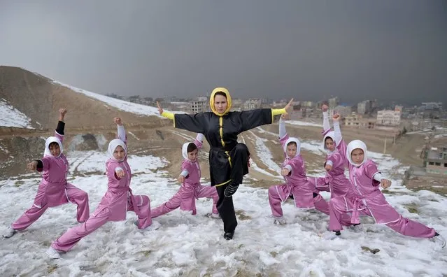 In this photograph taken on January 29, 2017, Afghan members of a wushu martial arts group led by trainer Sima Azimi (C), 20, pose for a photograph at the Shahrak Haji Nabi hilltop overlooking Kabul. Afghanistan's first female wushu trainer, Sima Azimi, 20, is training 20 Afghan girls aged between 14 – 20 at a wushu club in Kabul, after learning the sport while living as a refugee in Iran. (Photo by Wakil Kohsar/AFP Photo)