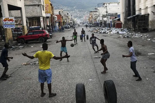 Youths play soccer next to businesses that are closed due to a general strike in Port-au-Prince, Haiti, Monday, October 18, 2021. (Photo by Matias Delacroix/AP Photo)