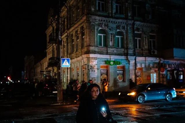 A local resident uses a flashlight as she walks in the street during a partial blackout in Kyiv on December 14, 2022, amid the Russian invasion of Ukraine. (Photo by Dimitar Dilkoff/AFP Photo)