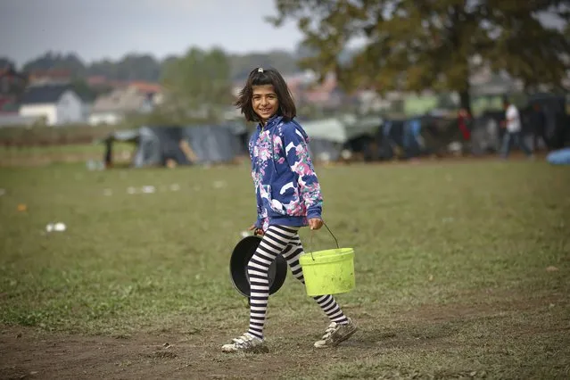 A migrant girl poses for a photograph at a makeshift camp housing migrants mostly from Afghanistan, in Velika Kladusa, Bosnia, Tuesday, October 12, 2021. Dozens of children of all ages are among migrants staying in a make-shift tent camp in northwest Bosnia in cold fall weather while waiting for a chance to move on toward Western Europe. Across a wide field dotted with improvised shelter, toddlers could be seen clinging to their toys on cold mornings. (Photo by AP Photo/Stringer)