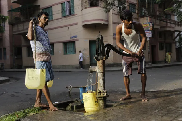 A water man or locally called as “bhari” fills drinking water from a roadside hand pump while another waits to deliver in houses in Kolkata, India, Tuesday, March 22, 2016. A report says India has the world's highest number of people without access to clean water. The international charity Water Aid says 75.8 million Indians or 5 percent of the country's 1.25 billion population are forced to either buy water at high rates or use supplies that are contaminated with sewage or chemicals. (Photo by Bikas Das/AP Photo)