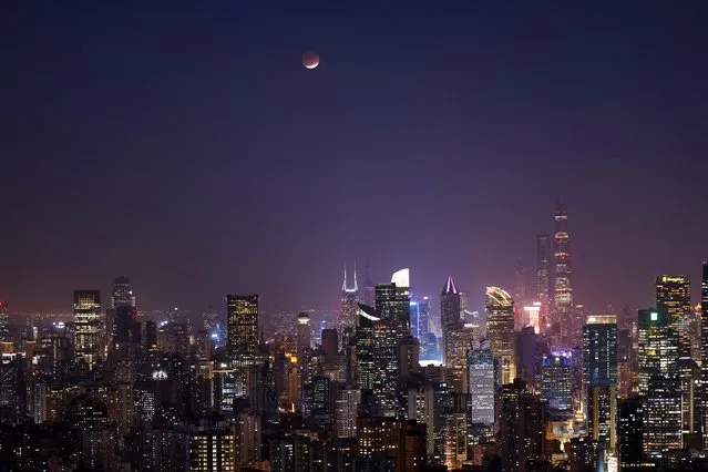 Lunar eclipse rises over the skyline of Shanghai, China on November 19, 2021. (Photo by Aly Song/Reuters)