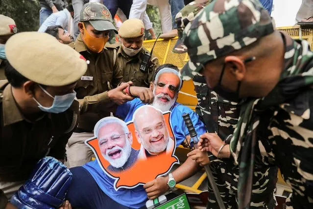 A police officer tries to detain a supporter of the youth wing of India's main opposition Congress Party wearing a cut-out of Prime Minister Narendra Modi during a protest against what they say is rising inflation in the country in New Delhi, India, December 1, 2021. (Photo by Anushree Fadnavis/Reuters)