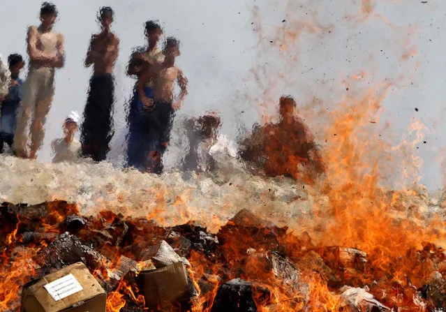 Afghan children look at a burning pile of 5 tons of expired medicines, on the outskirts of Jalalabad, east of Kabul, Afghanistan, Tuesday, September 7, 2010. (Photo by Rahmat Gul/AP Photo)