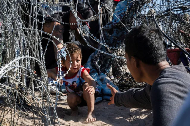 A young boy crawls through a concertina wire at the border as migrants cross from Mexico into El Paso, Texas, U.S. March 22, 2024. (Photo by Justin Hamel/Reuters)
