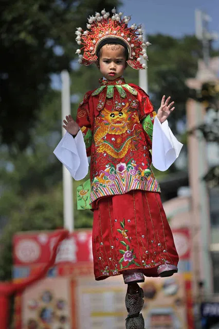 A child dressed in a traditional Chinese costume floats in the air, supported by a rig of hidden metal rods, during a parade on the outlying Cheung Chau island in Hong Kong to celebrate the Bun Festival Sunday, May 12, 2019. Thousands of local residents and tourists flocked to an outlying island in Hong Kong to celebrate a local bun festival on Sunday despite the recording-breaking heat. The festival features a parade with children dressed as deities floated on poles. Contestants will take part in bun-scrambling competition. They will race up a 14-meter bamboo tower to snatch as many plastics buns as possible. Buns that are higher up are worth more points. (Photo by Vincent Yu/AP Photo)