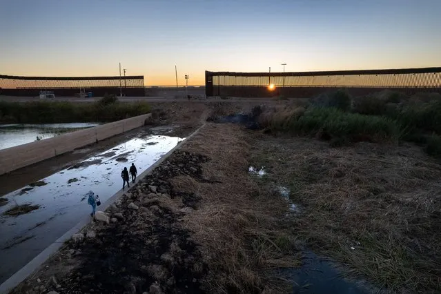 In an aerial view, a immigrant family from Haiti walks towards a gap in the U.S. border wall from Mexico on December 11, 2021 in Yuma, Arizona. They had made the arduous journey from Brazil. Yuma has seen a surge of migrant crossings in the past week, with many immigrants trying to reach U.S. soil before the court-ordered re-implementation of the Trump-era Remain in Mexico policy. The policy requires asylum seekers to stay in Mexico during their U.S. immigration court process. (Photo by John Moore/Getty Images)