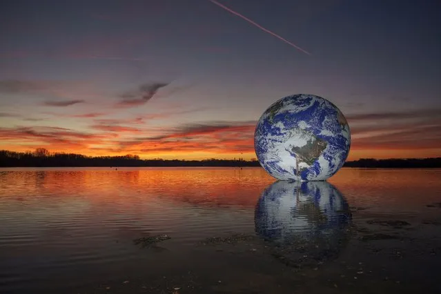 The sun sets behind artist Luke Jerram's “Floating Earth” at Pennington Flash on November 22, 2021 in Wigan, England. The floating Earth will hover over Pennington Flash for 10 days from November 19, as part of a celebration of Wigan and Leigh's watercourses and is the first time one of Jerram's globes has been floated on an open expanse of water. (Photo by Christopher Furlong/Getty Images)