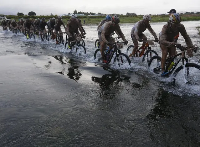 Riders cross a river after heavy overnight rain turned the trail into mud during stage 2 of the annual ABSA Cape Epic mountain bike stage race near Cape Town, South Africa, 25 March 2014. (Photo by Kim Ludbrook/EPA)
