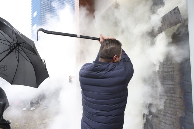 Employees of Democrats' Party use a fire extinguisher against protesters who try to invade at the headquarters in Tirana, Albania, Saturday, January 8, 2022. (Photo by Franc Zhurda/AP Photo)