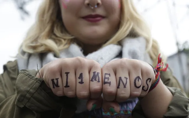 A woman shows her knuckles with the words “Not one less” painted on them during an International Women's Day demonstration in Quito, Ecuador, Wednesday, March 8, 2017. (Photo by Dolores Ochoa/AP Photo)