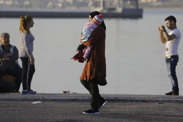 A mother holds her baby as other migrants take photographs after being picked up by the Greek coast guard at the port of Mitylene, on the northeast Greek island of Lesvos on Wednesday, June 17, 2015. Around 100,000 migrants have entered Europe so far this year as Italy and Greece have borne the brunt of the surge with many more migrants expected to arrive from June through to September. (AP Photo/Thanassis Stavrakis)