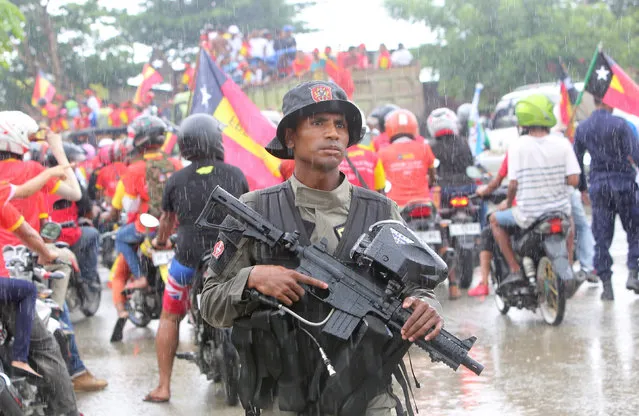 A policeman stands guard on March 17, 2017 as supporters of presidential candidate Francisco Guterres from the Revolutionary Front for an Independent East Timor party ride through the street campaigning ahead of next week’s elections in Dili, East Timor. (Photo by Lirio Da Fonseca/Reuters)