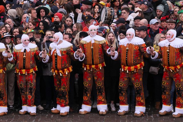 Spectators stand behind people wearing “Gilles” masks and costumes during the Binche carnival, a UNESCO World Heritage event, in Binche, Belgium on February 21, 2023. (Photo by Yves Herman/Reuters)