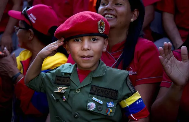 A boy dressed in a military costume salutes toward the camera during an event marking President Nicolas Maduro's first year in office in Caracas, Venezuela, Tuesday, April 15, 2014. Maduro took over leadership of Hugo Chavez's political movement following the leader's death from cancer and went on to win elections soon after in April 2013. (Photo by Ramon Espinosa/AP Photo)