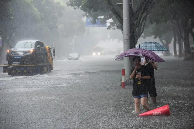 People holding umbrellas wade through floodwaters amid heavy rainfall on a street after super typhoon Lekima made landfall in Ningbo, Zhejiang province, China on August 10, 2019. (Photo by Reuters/China Stringer Network)