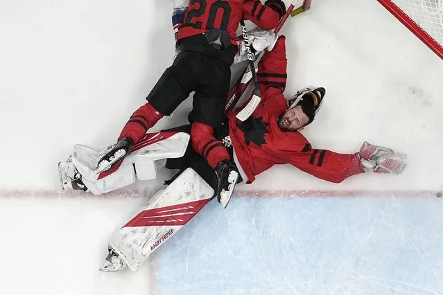 Canada goalkeeper Eddie Pasquale is knocked down by teammate Alex Grant (20) during a preliminary round men's hockey game against the United States at the 2022 Winter Olympics, Saturday, February 12, 2022, in Beijing. (Photo by Matt Slocum/AP Photo)