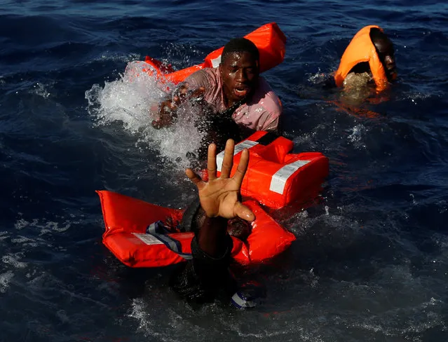 Migrants try to stay afloat after falling off their rubber dinghy during a rescue operation by the Malta-based NGO Migrant Offshore Aid Station (MOAS) ship in the central Mediterranean in international waters some 15 nautical miles off the coast of Zawiya in Libya, April 14, 2017. All 134 sub-Saharan migrants survived and were rescued by MOAS. (Photo by Darrin Zammit Lupi/Reuters)