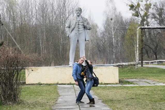 In this photo taken Wednesday, April 5, 2017, journalists take a selfie in front of the monument of Soviet state founder Vladimir Lenin in Chernobyl, Ukraine. April 26 marks the 31st anniversary of the Chernobyl nuclear disaster. A reactor at the Chernobyl nuclear power plant exploded on April 26, 1986, leading to an explosion and the subsequent fire spewed a radioactive plume over much of northern Europe. (Photo by Efrem Lukatsky/AP Photo)