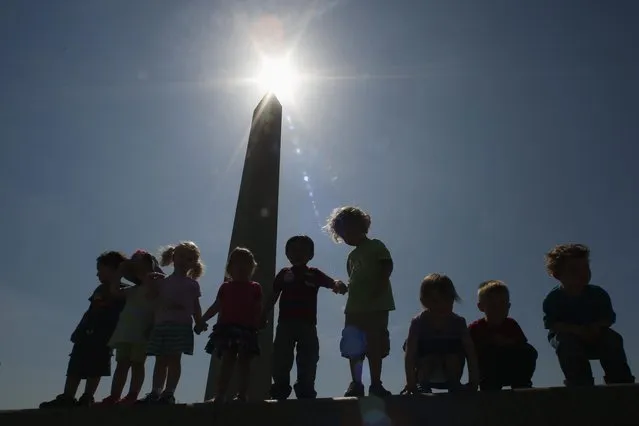 Children play up on a wall during the re-opening ceremony for the Washington Monument in Washington May 12, 2014. The monument was closed in 2011 after it suffered widespread damage caused by a 5.8 magnitude earthquake along the East Coast. (Photo by Kevin Lamarque/Reuters)