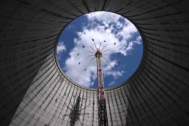 Visitors ride a merry-go-round at the amusement park 'Wunderland Kalkar' (Wonderland Kalkar) in Kalkar, western Germany on April 11, 2023. Wunderland Kalkar was a nuclear fast breeder (Schneller Brueter), which was completed but never taken online until 1991, and in 1995 Dutch investor Hennie van der Most bought it and transformed into an amusement park. (Photo by Ina Fassbender/AFP Photo)