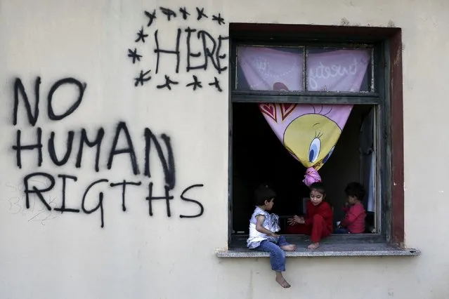 Children sit on a window sill at a makeshift camp for refugees and migrants at the Greek-Macedonian border near the village of Idomeni, Greece, May 19, 2016. (Photo by Kostas Tsironis/Reuters)