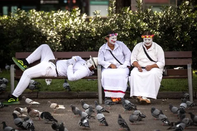 Mime artists relax at lunchtime on a park bench in Catalonia Square in central Barcelona, Spain, Wednesday, October 23, 2019. (Photo by Ben Curtis/AP Photo)
