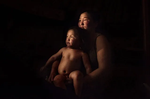 Asia, Mongolia, March 18, 2011. Erdene Tuya, 29 years old together with is son Tuvchinj, 3 years old, during the night just before to go sleep. (Photo by Alessandro Grassani)