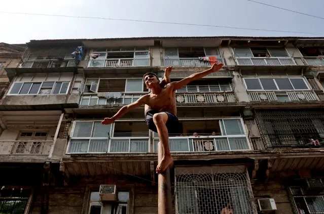 A boy performs “Malkhamb” (traditional Indian gymnastics) during celebrations to mark the Gudi Padwa festival, the beginning of the New Year for Maharashtrians, in Mumbai, India, April 2, 2022. (Photo by Niharika Kulkarni/Reuters)