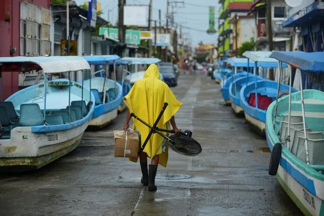 A man carries a fan and a box while walking past tourist boats that were moved from the water for safety as Hurricane Grace gathered more strength before reaching land, in Tecolutla, Mexico on August 20, 2021. (Photo by Oscar Martinez/Reuters)