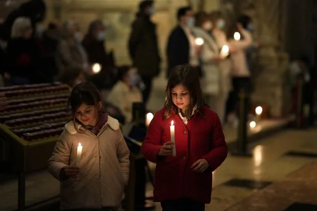 Two young girls hold candles while worshippers pray for peace in Ukraine at Lisbon's 16th century Jeronimos Monastery, Friday night, March 11, 2022. Thousands of people have been killed and more than 2.3 million have fled the country since Russian troops crossed into Ukraine on Feb. 24. (Photo by Armando Franca/AP Photo)