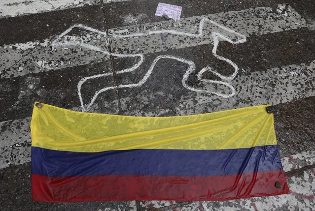 A Colombian national flag lays at the site where Dilan Cruz was injured during clashes between anti-government protesters and security forces, in Bogota, Colombia, Tuesday, November 26, 2019. Cruz, an 18-year-old high school student, died two days after being hit in the head by a projectile reportedly fired by riot police during a protest. His case has resonated in Colombian society, touching off a debate about excessive use of force and making him a symbol for many young protesters. (Photo by Fernando Vergara/AP Photo)