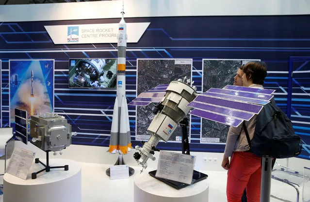 Visitors watch the booth of Russian Federal Space Agency Roscosmos displaying models of satellites at the ILA Berlin Air Show in Schoenefeld, south of Berlin, Germany, June 1, 2016. (Photo by Fabrizio Bensch/Reuters)