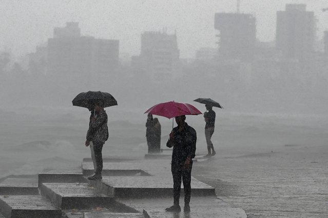 People enjoy rain showers near the sea front in Mumbai on July 8, 2024. Intense monsoon storms battered India on July 8, flooding parts of the financial capital Mumbai, while lightning in the eastern state of Bihar killed at least 10 people, government officials said. (Photo by Punit Paranjpe/AFP Photo)