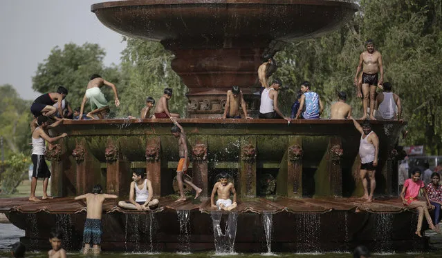 Indians cool off themselves at a fountain near the India Gate monument on a hot day in New Delhi, India, Tuesday, June 6, 2017. (Photo by Altaf Qadri/AP Photo)
