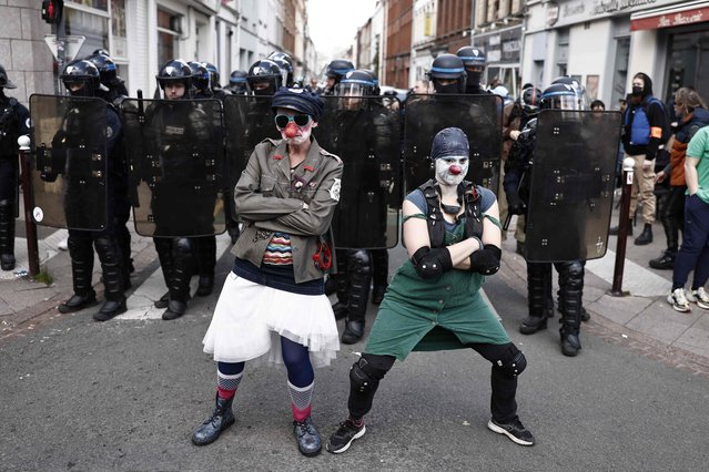 Protesters dressed as clowns pose in front of French police in riot gear as they take part in a demonstration on May Day (Labour Day), to mark the international day of the workers, more than a month after the government pushed an unpopular pensions reform act through parliament, in Lille, northern France, on May 1, 2023. Opposition parties and trade unions have urged protesters to maintain their three-month campaign against the law that will hike the retirement age to 64 from 62. (Photo by Sameer Al-Doumy/AFP Photo)