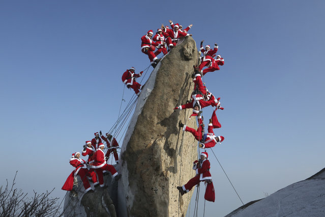Mountain climbers in Santa Claus outfits pose during an event to hope for safe climbing and to promote Christmas charity on the Buckhan mountain in Seoul, South Korea, Sunday, December 22, 2019. (Photo by Ahn Young-joon/AP Photo)