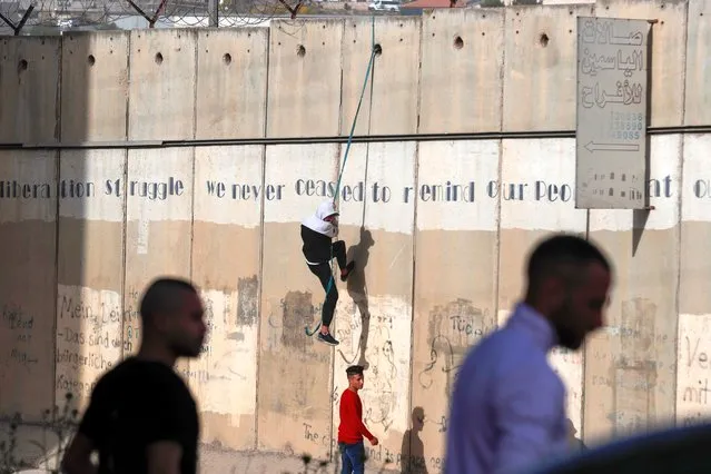Palestinian men trying to jump over the separation barrier between the Palestinian town of A-Ram and Jerusalem, to attend the last Friday prayer of the Muslim holy month of Ramadan in Al Aqsa Mosque in Jerusalem’s old city, 29 April 2022. (Photo by Atef Safadi/EPA/EFE)
