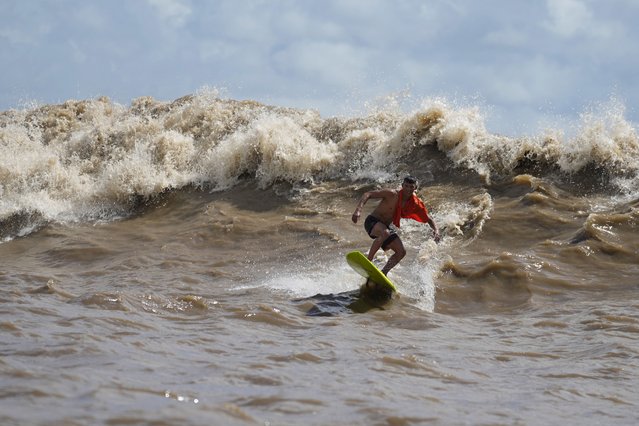 Brazilian surfer Naysson Costa rides the tidal bore wave known as “Pororoca”, during the Amazon Surf Festival held in the Canal do Perigoso, or “Dangerous Channel”, at the mouth of the Amazon River near Chaves, Marajo Island archipelago, Para state, Brazil, Monday, June 5, 2023. The Pororoca, a word from an Amazonian Indigenous dialect that means “destroyer” or “great blast”, happens twice a day when the incoming ocean tide reverses the river flow for a time. (Photo by Eraldo Peres/AP Photo)