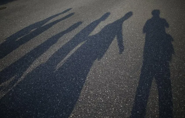 Reuters photographer Issei Kato (R) and passersby cast shadows on a street in Hiroshima, western Japan July 28, 2015. (Photo by Issei Kato/Reuters)