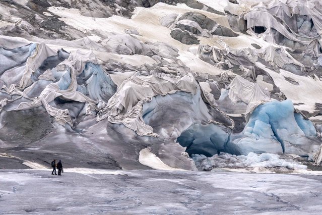 Team members of ETH (Swiss Federal Institute of Technology) glaciologist and head of the Swiss measurement network “Glamos”, Matthias Huss, arrive at the Rhone Glacier partially covered near Goms, Switzerland, Friday, June 16, 2023. (Photo by Matthias Schrader/AP Photo)