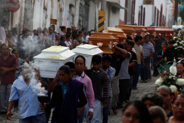 Relatives and friends carry the coffins of some of the eleven members of the same family, including two children, who were killed in the central Mexican state of Puebla when gunmen burst into their home, during their funeral along the streets in Coxcatlan, Mexico June 13, 2016. (Photo by Reuters/Stringer)
