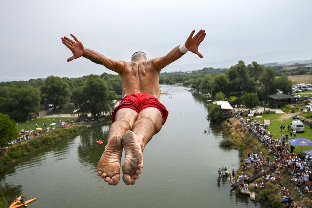 A competitor jumps from the 22-meter-high “Ura e Shenjte” bridge, or Sacred Bridge, during the annual traditional High Diving competition near the town of Gjakova, on August 18, 2024. (Photo by Armend Nimani/AFP Photo)