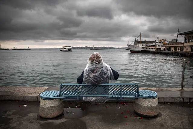 A person sits on the Kadikoy dock bench in the rain, on the second day of the Eid al-Fitr festival in Istanbul, Turkey on May 3, 2022. (Photo by Onur Dogman/SOPA Images/Rex Features/Shutterstock)