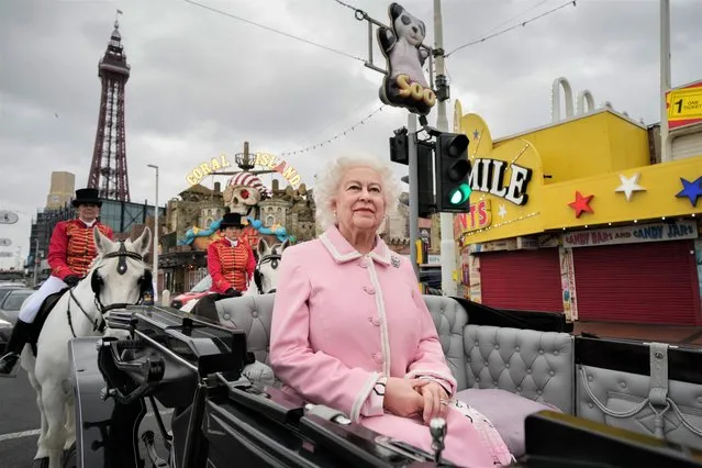 A waxwork of Queen Elizabeth II is escorted in a horse and carriage along the promenade as it makes it's way to Madame Tussauds on October 14, 2021 in Blackpool, England. The new waxwork replaces the figure created in 2012 to celebrate the Queen's Diamond Jubilee, when it first appeared in Madame Tussauds Blackpool. (Photo by Christopher Furlong/Getty Images)