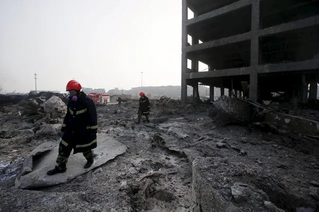 Firefighters wearing gas masks walk next to a damaged building among debris at the site of Wednesday night's explosions in Binhai new district of Tianjin, China, August 15, 2015. (Photo by Reuters/China Daily)
