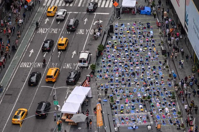 Yogis take part in a Solstice in “Times Square: Mind Over Madness Yoga” event marking the summer solstice, in Times Square, New York on June 21, 2022. (Photo by Ed Jones/AFP Photo)