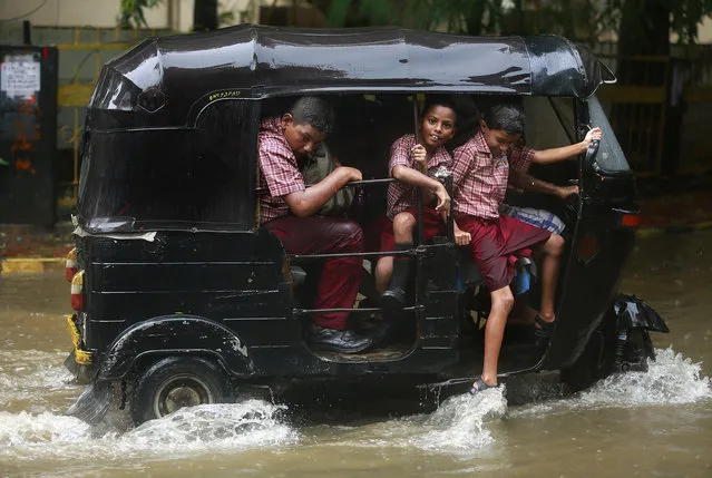School children ride an auto rickshaw through a flooded street as it rains in Mumbai, India, Tuesday, June 28, 2016 . Monsoon rains, which started off slow in the city, has picked up pace the past few days. India's monsoon season runs from June to September. (Photo by Rafiq Maqbool/AP Photo)